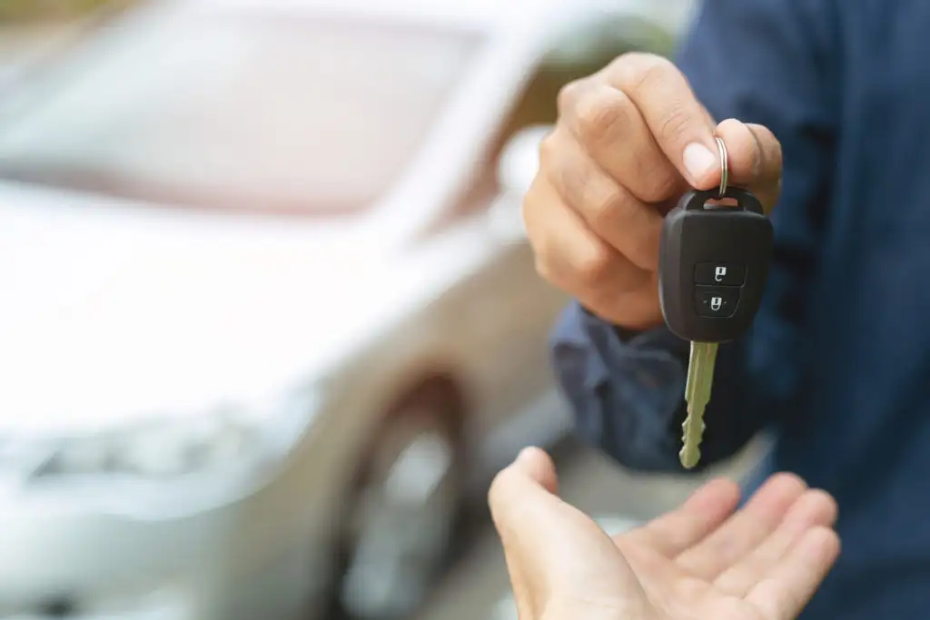 Close up of person handing another person keys to a rental car