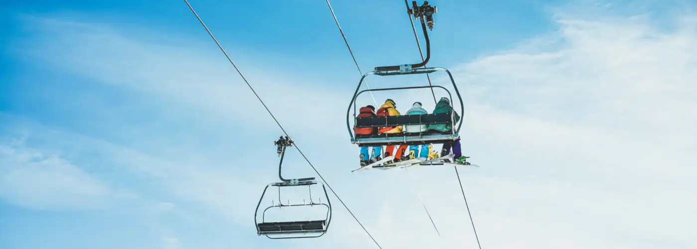 People on ski lift going up snowy mountain