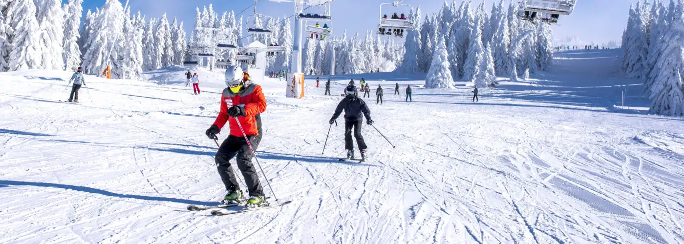 People skiing on a snowy mountain below a ski lift