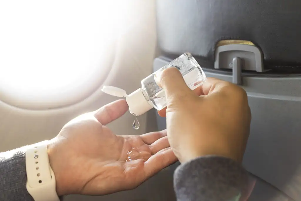 Close up of person's hands as they put on hand sanitizer on an airplane