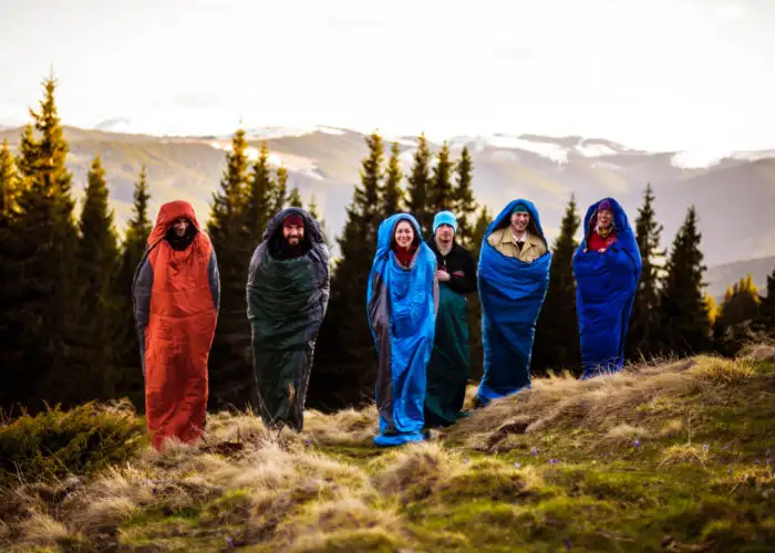 Group of people jumping in sleeping bags on a tree lined hill