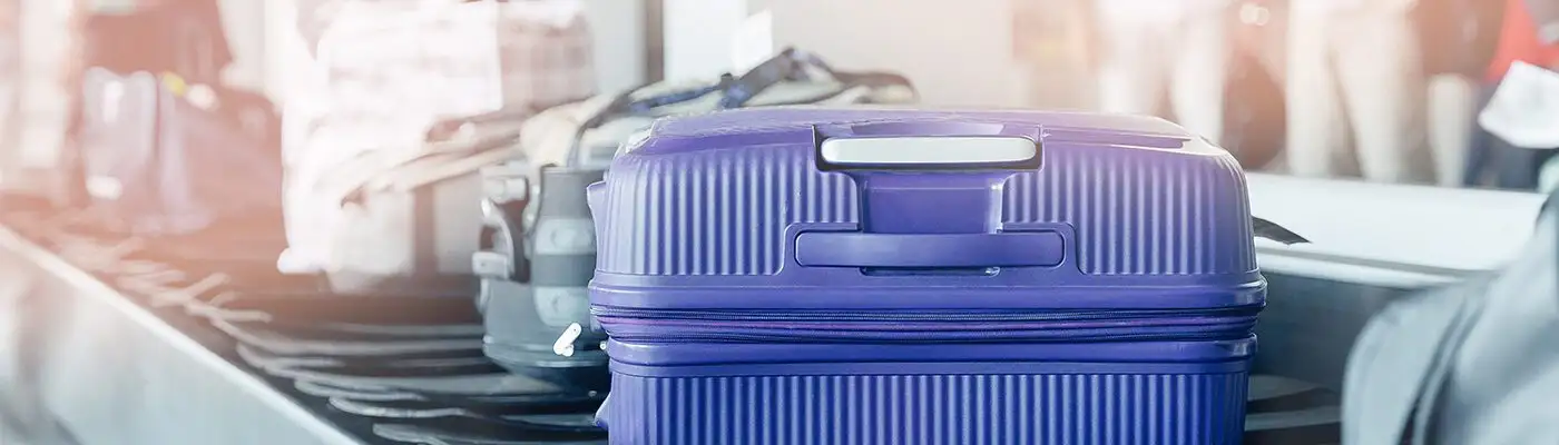 Hardside blue suitcase coming down the conveyor belt at baggage claim