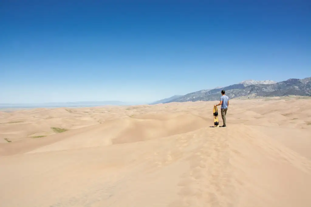 Person holding a sandboard in Great Sand Dunes National Park