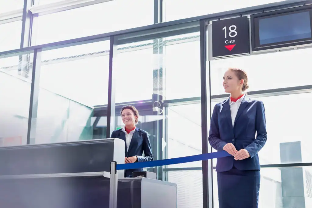 Two gate agents standing near desk at airport terminal