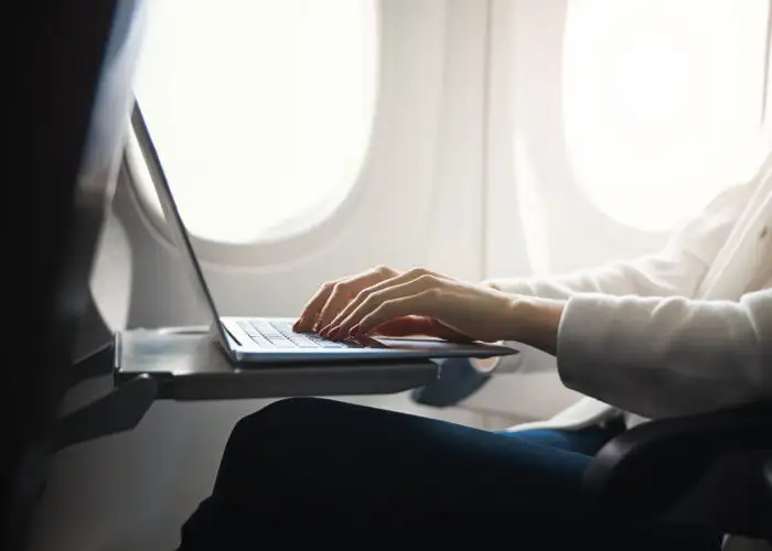 Close up of person working on a laptop on an airplane