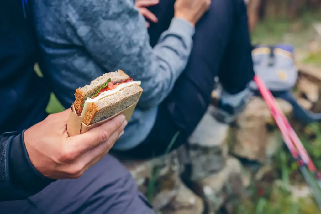 Close up of hikers holding deli meat sandwiches