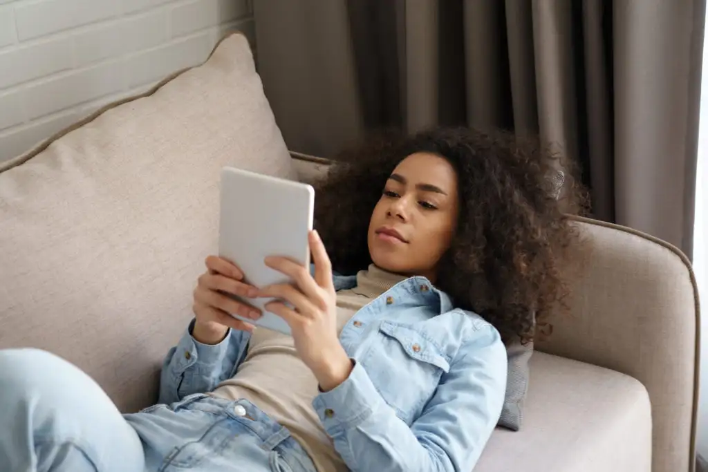 Woman reading an from an eReader while laying on a couch