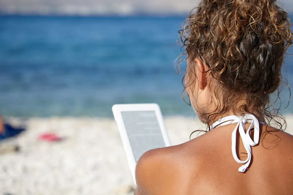 Woman reading from eReader on the beach