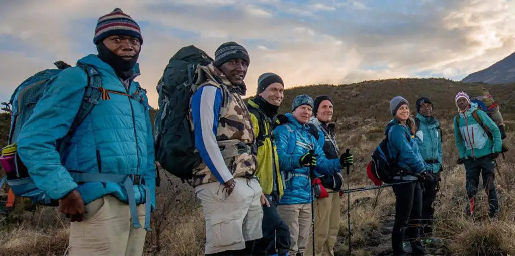 Hiking group and guide setting off on hike up Mount Kilimanjaro