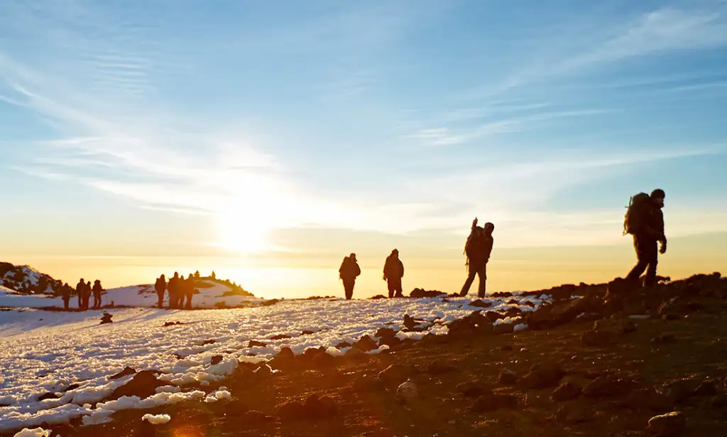 Group hiking an icy area on Mount Kilimanjaro at sunset
