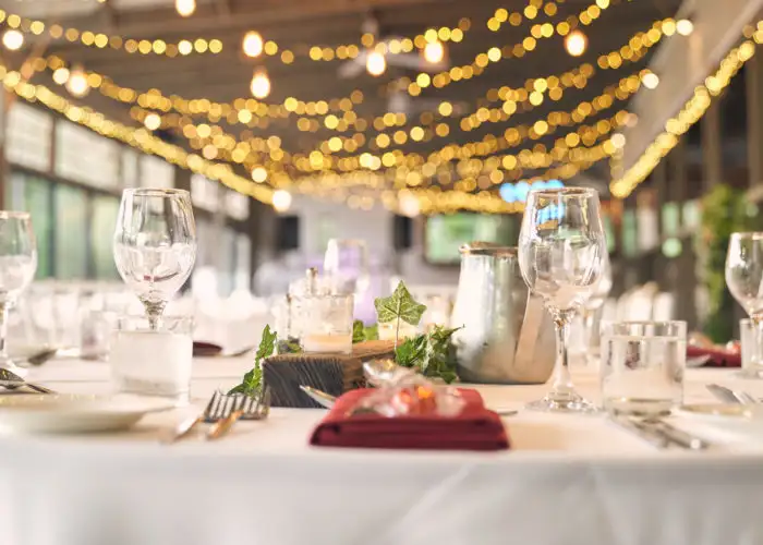 Close up of table decor for a wedding with twinkle string lights out of focus in the background