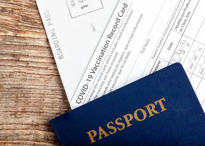 Passport and COVID vaccination card on wooden table