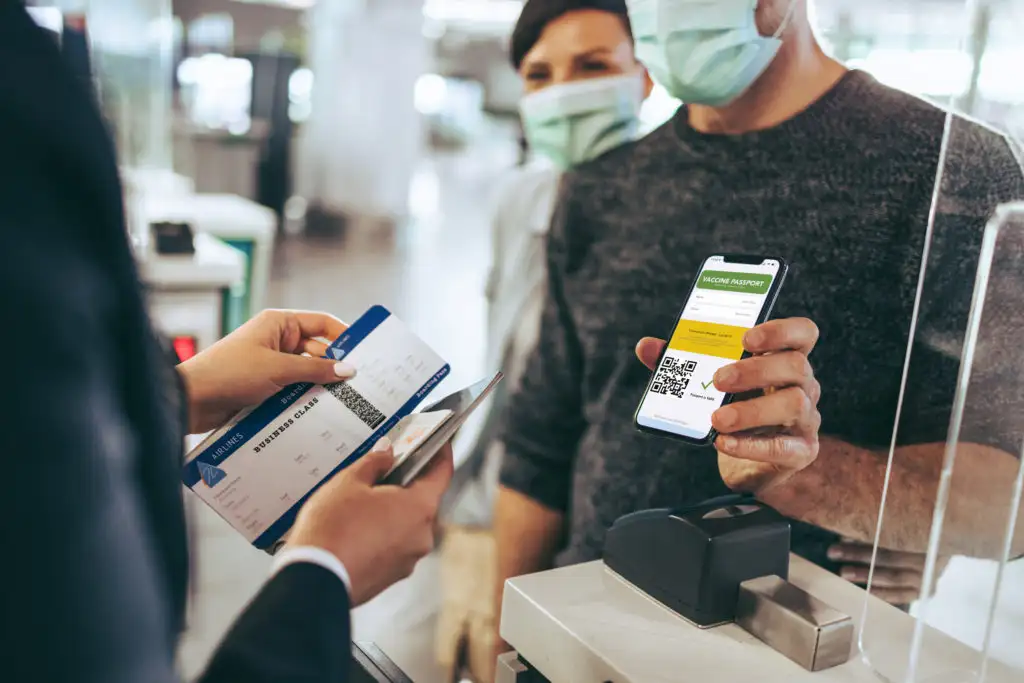 Man showing certification of COVID vaccine on cellphone to a gate agent at airport