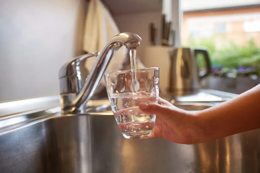 Close up of hand filling glass from tap