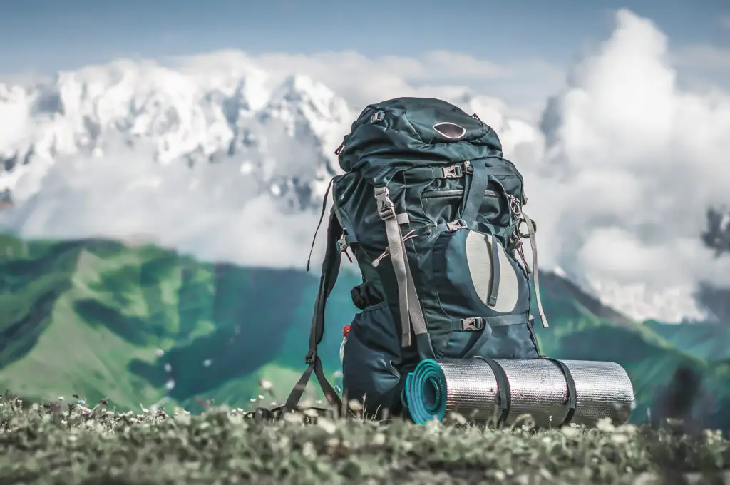 Backpack and hiking gear in front of a large mountain