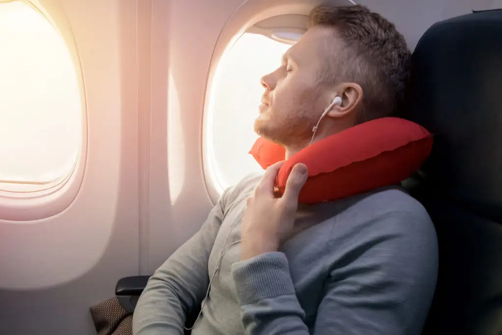 Man sleeping with neck pillow on airplane