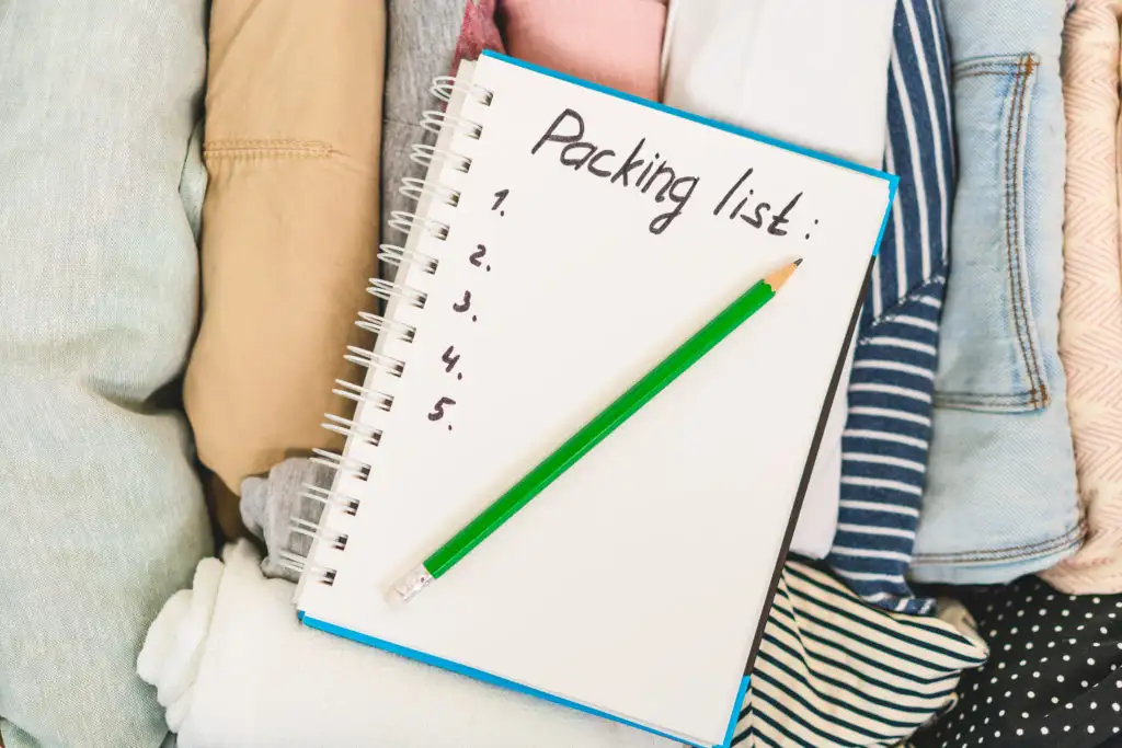 Blank packing list in a notebook on top of partially packed suitcase