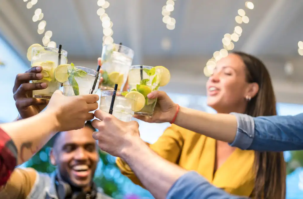 Group of friends clinking their drinking glasses and laughing