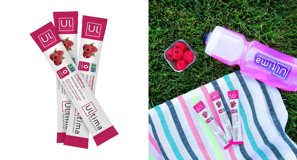 Packets of Ultima Replenisher Electrolyte Drink Mix and a Ultima branded water bottle next to Ultima Replenisher Electrolyte Drink Mix packets on a picnic blanket