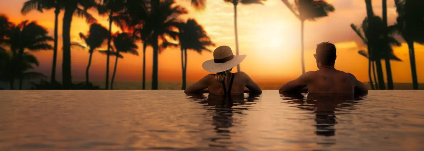 Couple looking over edge of infinity pool at sunset