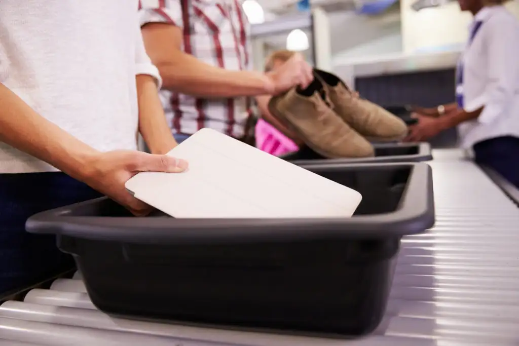 Person placing tablet into bin at airport security