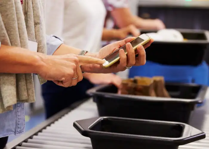 Person placing smartphone into bin at airport security