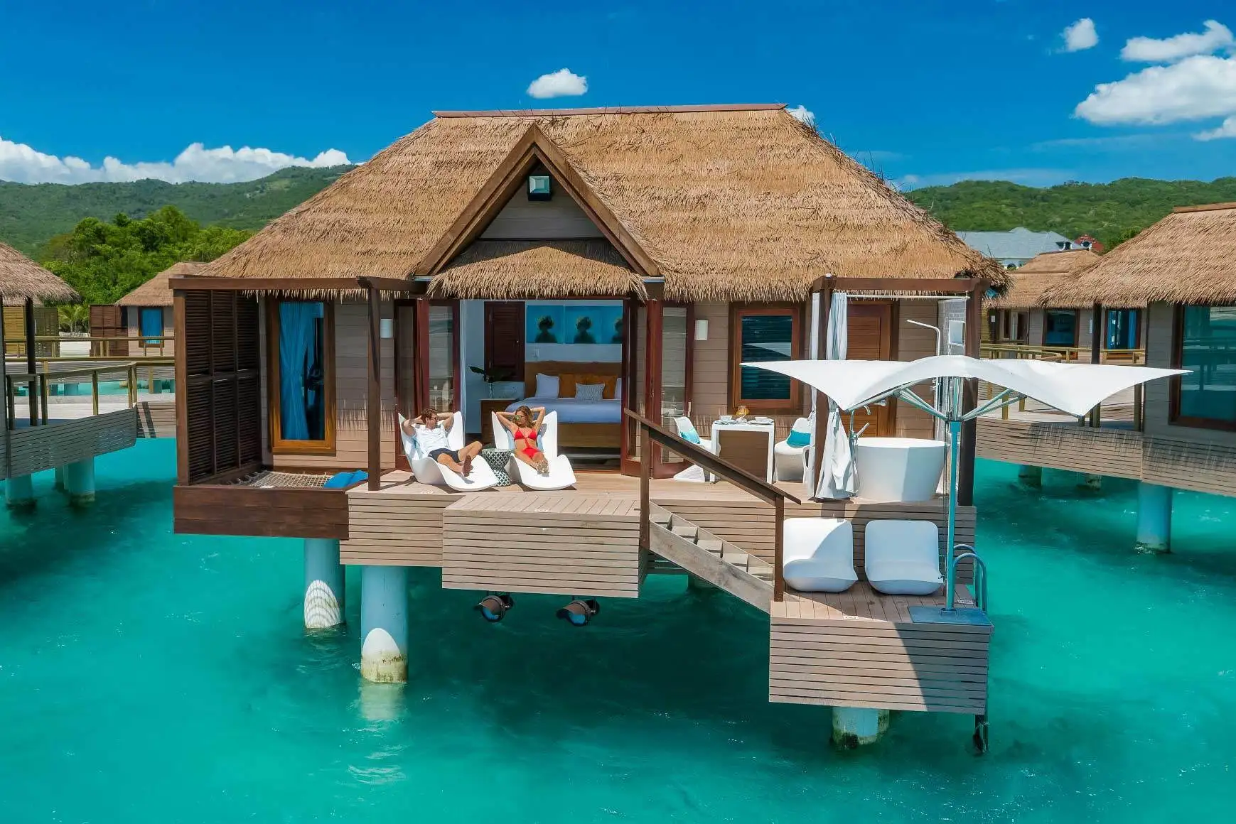 Two people resting on the deck of an overwater bungalow at Sandals South Coast in Jamaica