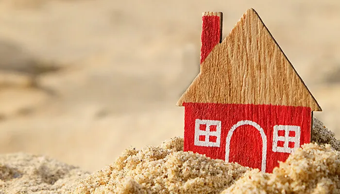 Small wooden model of a house in the sand