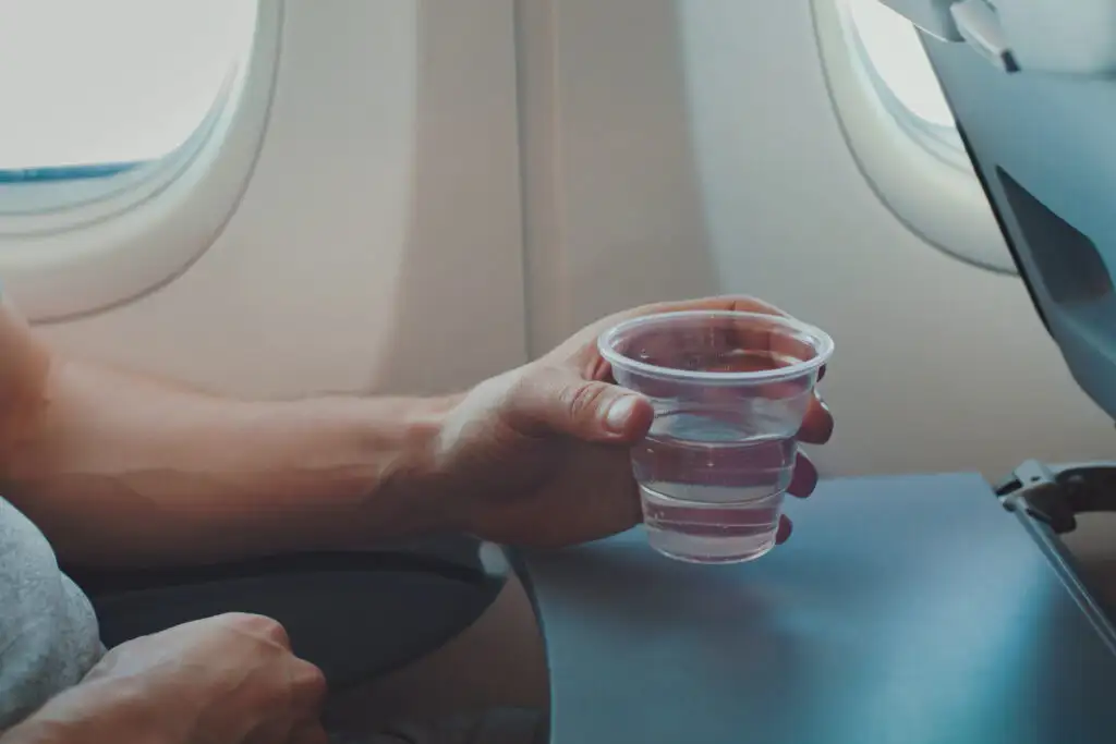 Close up of person holding a cup of water on an airplane