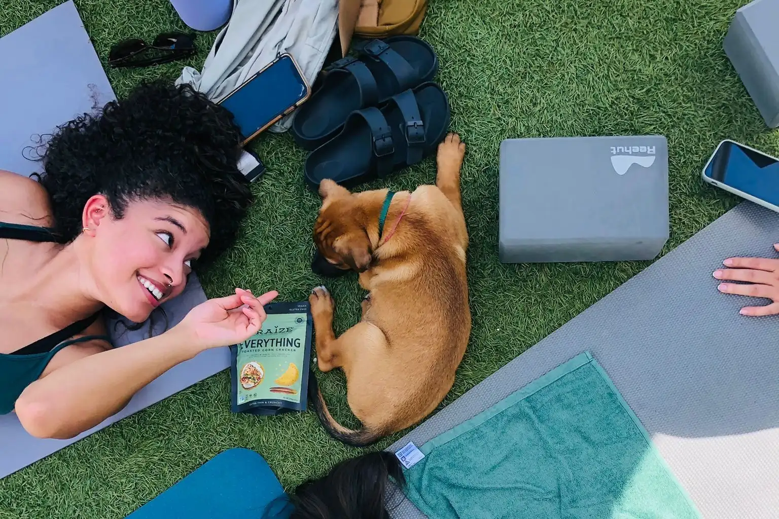 Aerial view of woman laying on yoga mat and looking at puppy, surrounded by exercise equipment
