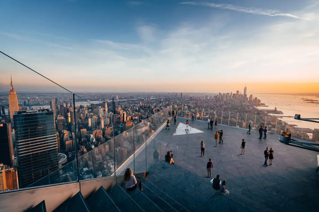 People walking around The Edge observation deck in New York City at sunset