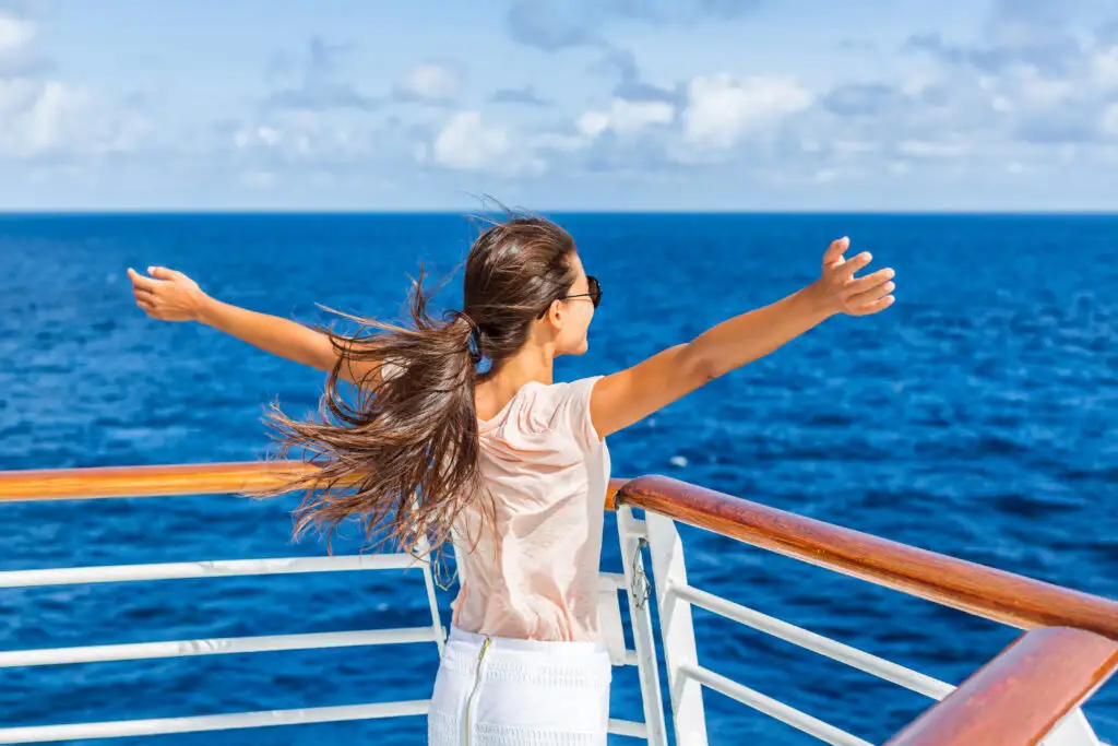 Woman with her arms outstretched at the bow of a cruise ship, overlooking the ocean