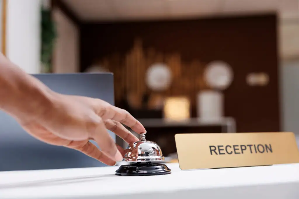 Close up of person ringing the bell at a hotel reception desk