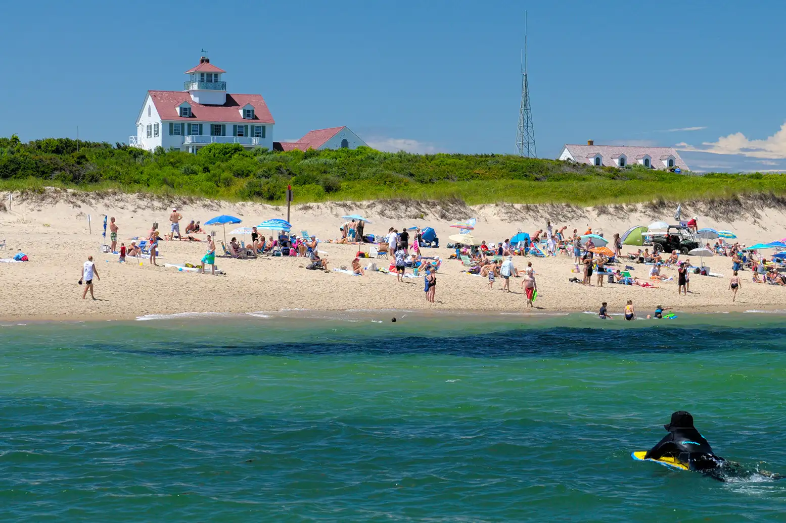People on Coast Guard Beach, Cape Cod, Massachusetts, with surfer in the water heading towards the beach.