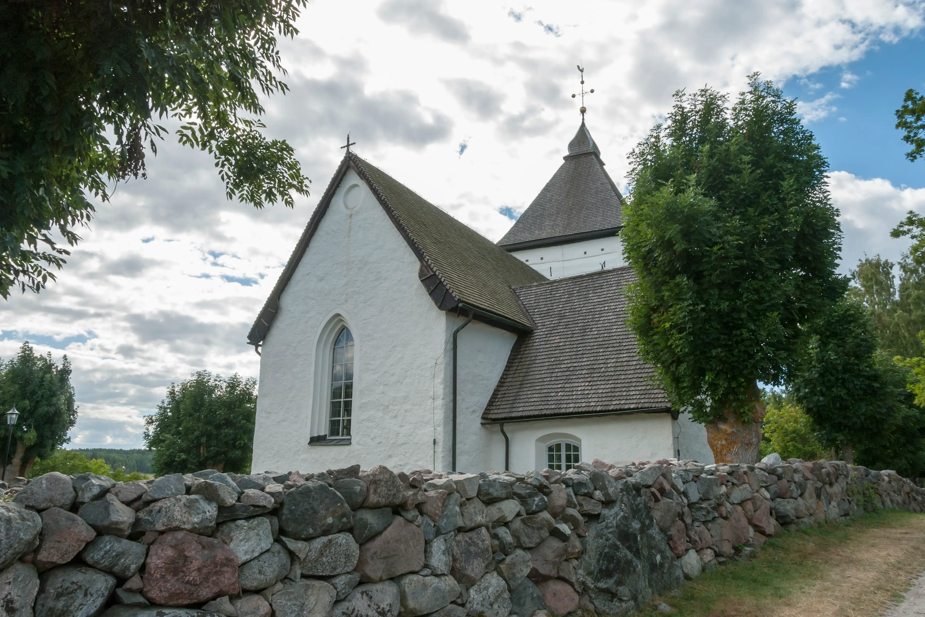  Old church in Hovgarden Sweden with rock wall in front.
