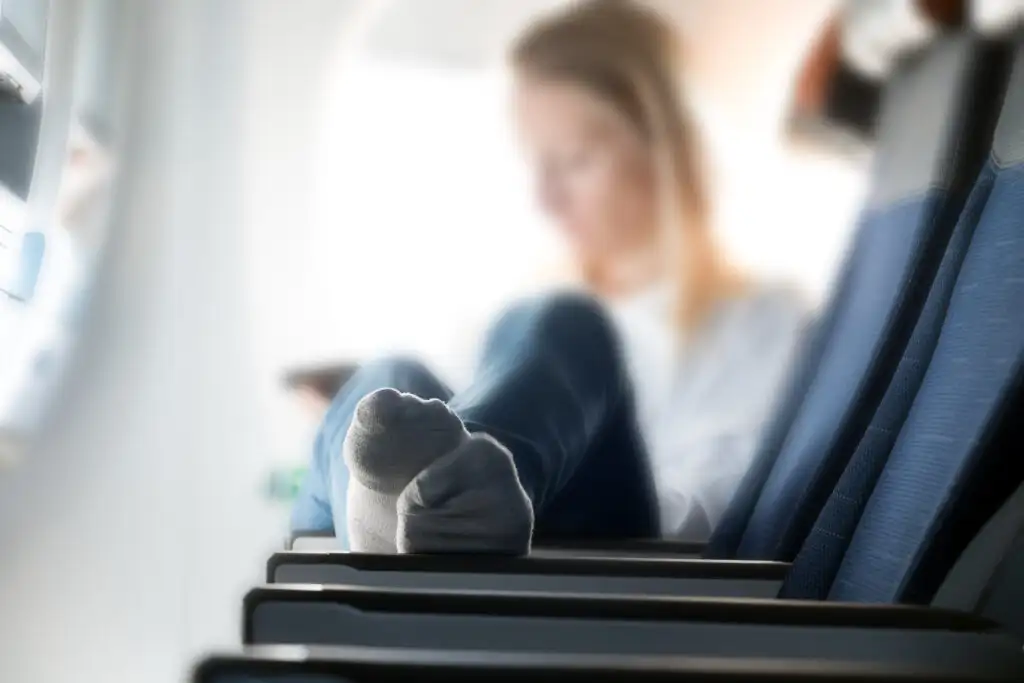 Close up of woman in socks putting her feet up on a row of airplane seats