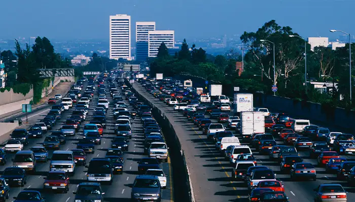 This is rush hour traffic on the 405 Freeway at sunset. There are 10 lanes of traffic total showing both sides of the freeway. There are cars stopped in every lane.