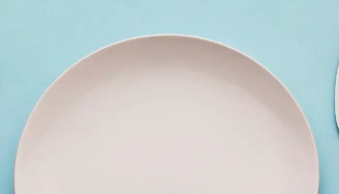 Empty fork, plate, and knife on blue background