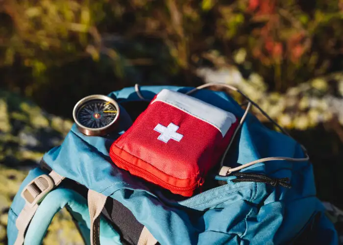Compass and first aid kit on a backpack in the woods