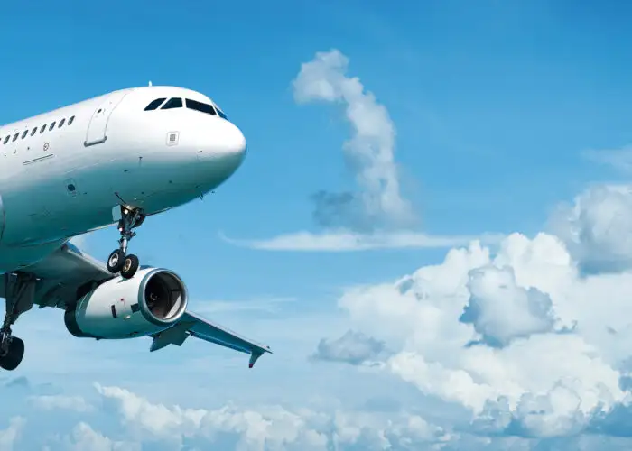 Airplane flying through a blue sky with white clouds