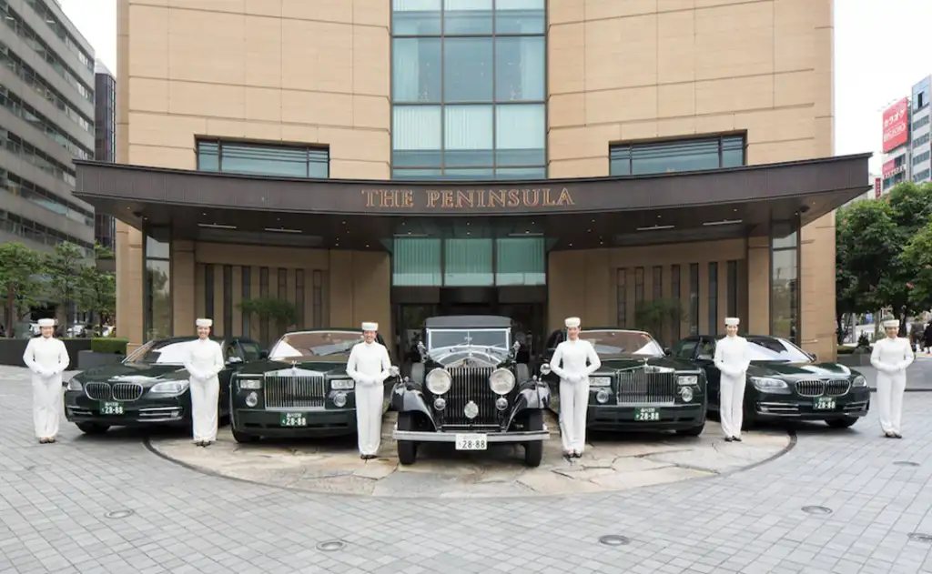Front entrance of The Peninsula Tokyo showcasing their fleet of luxury cars with drivers.
