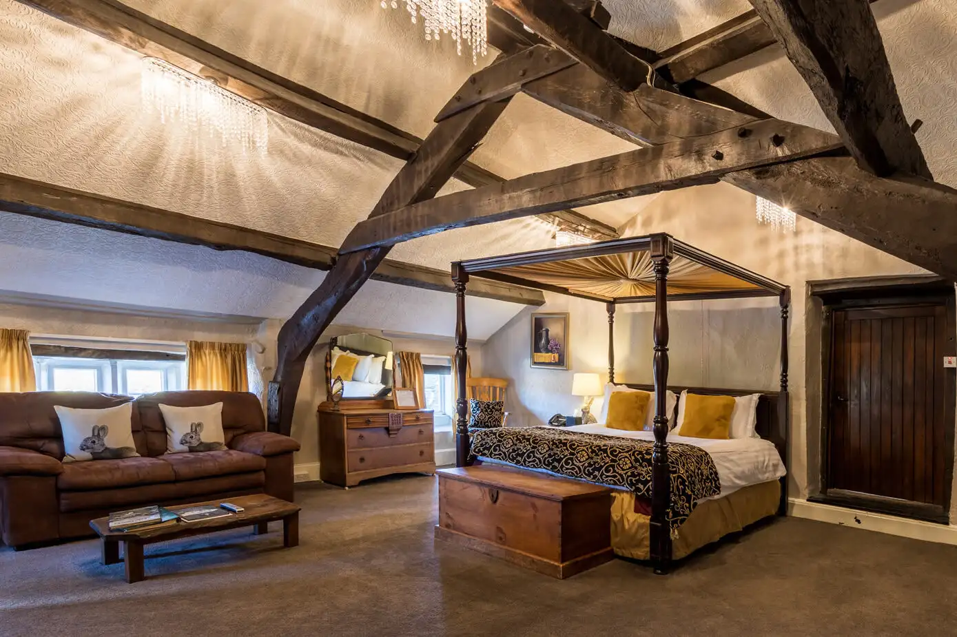 The Copley Suite at Gosforth Hall Inn, a rustic looking room with wooden beams, a large bed, and a couch