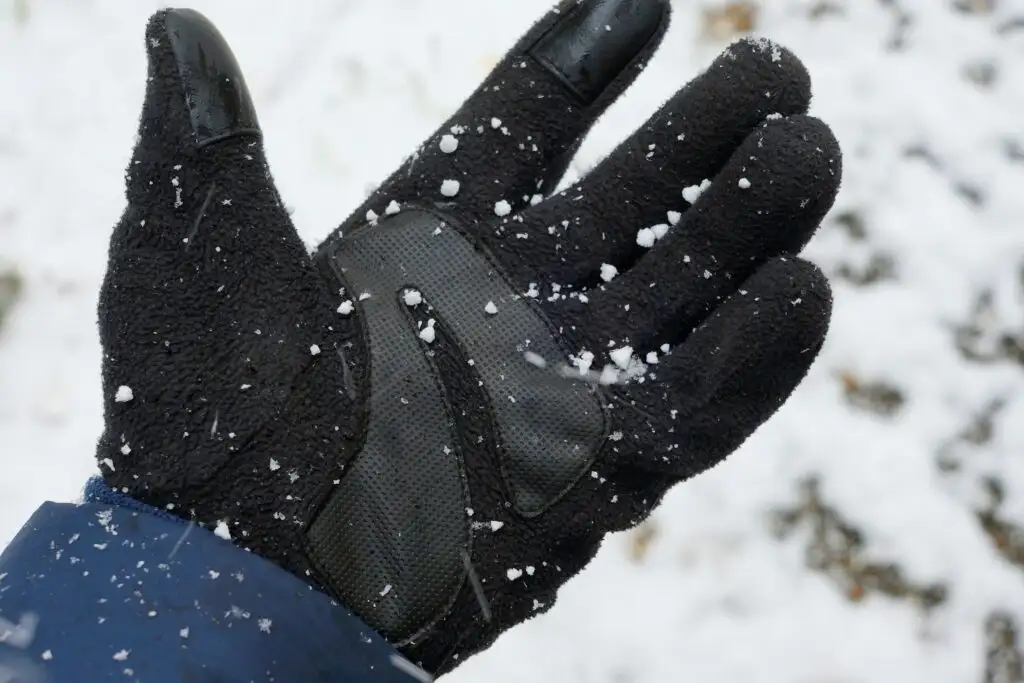Close up of hand wearing a black winter gloves in the snow