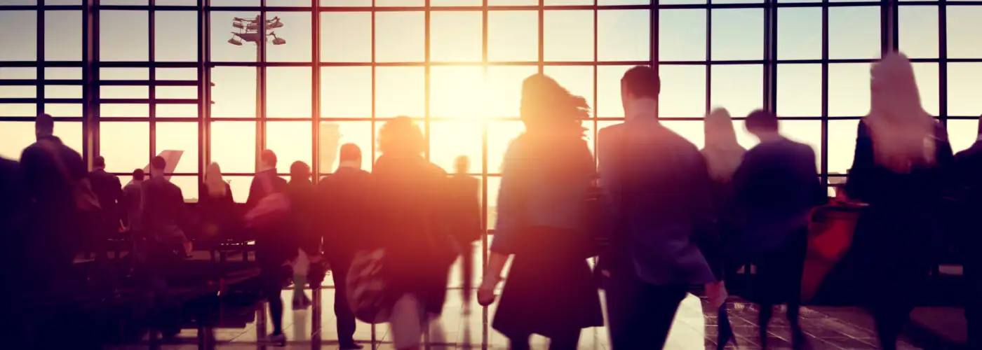 Silhouettes of people in a crowded airport at sunset