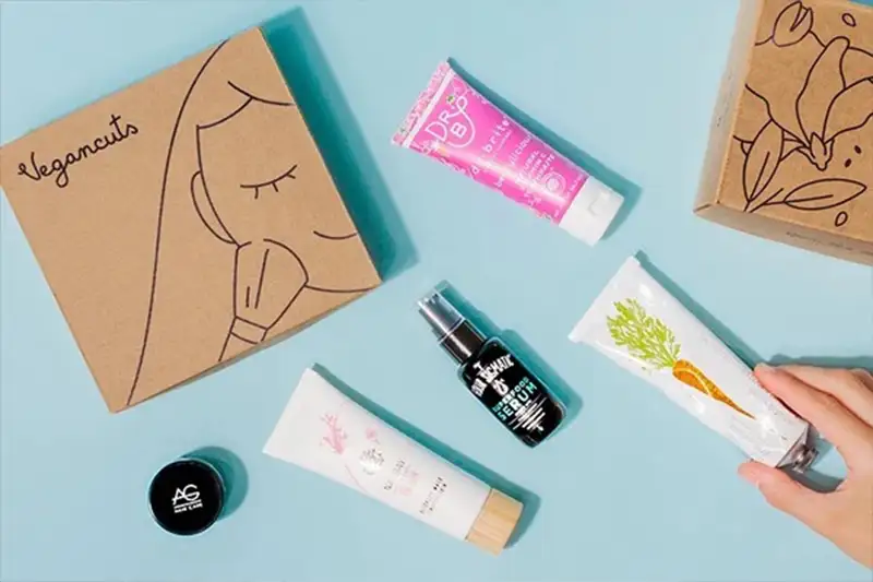The Vegancuts Beauty Box and various beauty products on a blue background