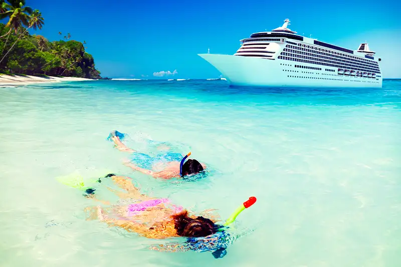 Couple snorkeling off shore with cruise ship in background