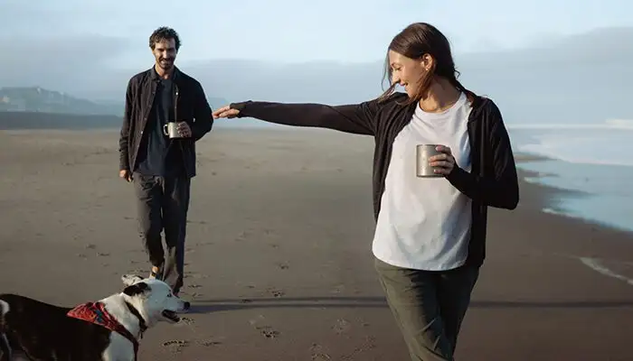 Couple walking along the beach with their dog wearing the Frost Pant from Kuhl
