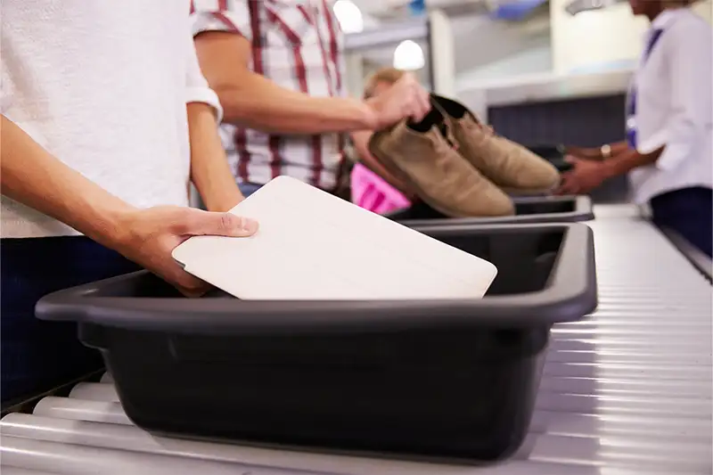 Person putting tablet in bin at airport security