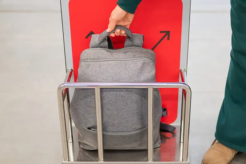 Person checking backpack in luggage size checker at airport terminal