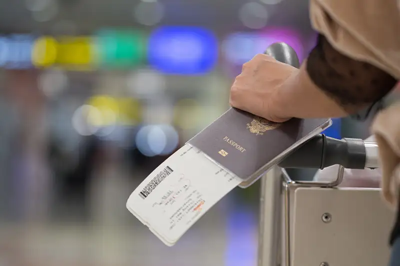 Close up of person holding passport and boarding pass at an airport